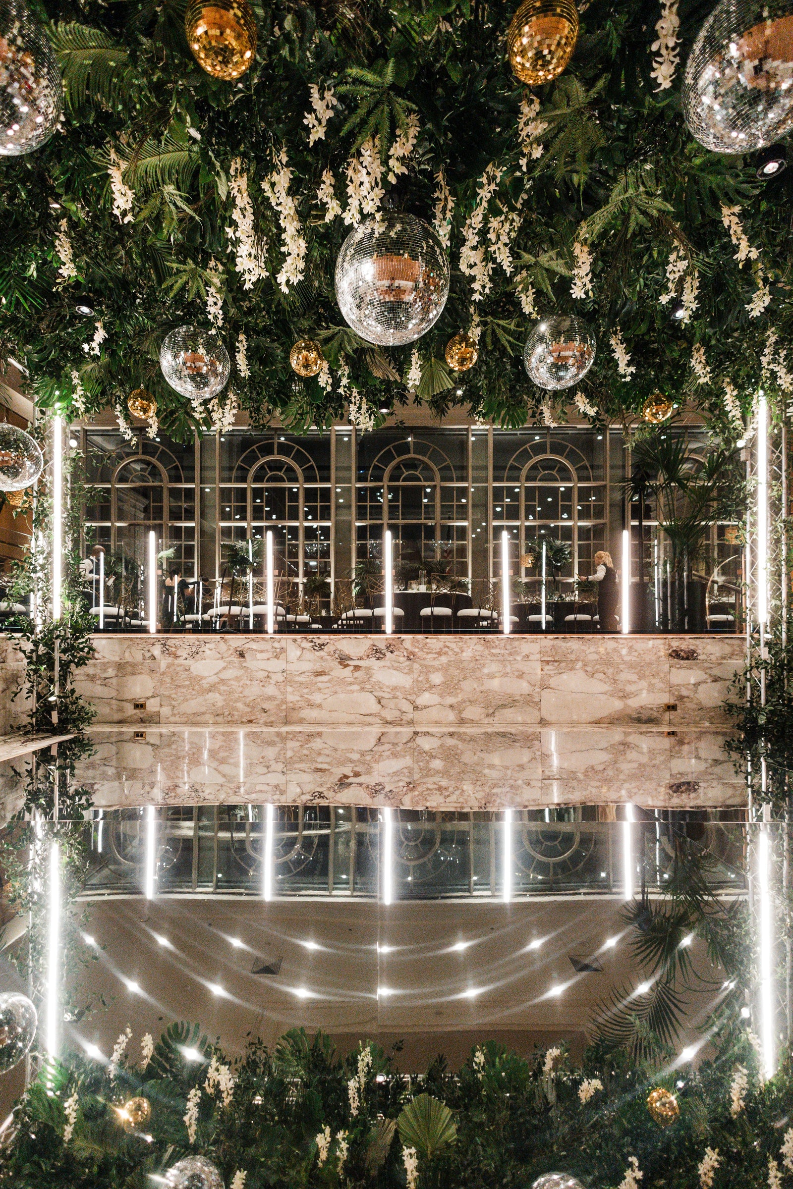 Event lighting featuring mirror balls, LED tubes, mirror floor and overhead floral installation at Fairmont Olympic Hotel 