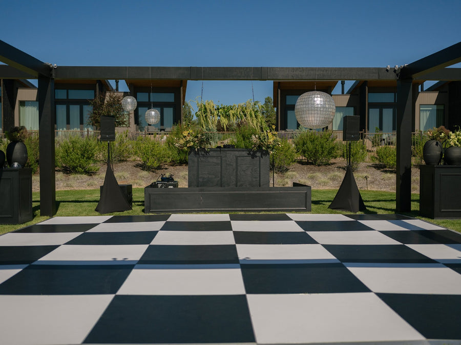 Black and white checkered wedding dance floor facing custom DJ booth with disco balls at Brasada Ranch, Bend Oregon – LightSmiths
